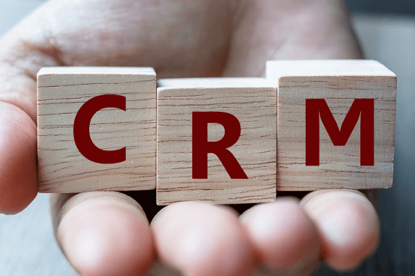 business-woman-hand-holding-wooden-cube-with-crm-t-B7PMTGA